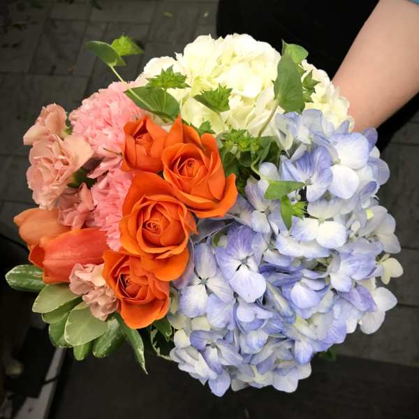 Bouquet of orange roses, pink carnations, and blue hydrangeas