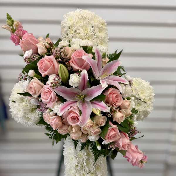Pink roses and lilies arranged in a white floral cross