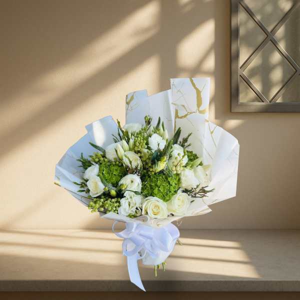 White and green bouquet wrapped in white paper with a ribbon