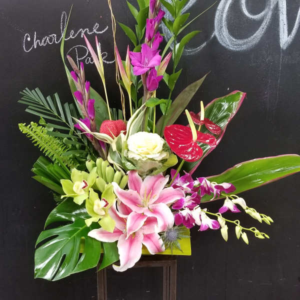 Tropical floral arrangement with pink lilies, orchids, and red anthuriums