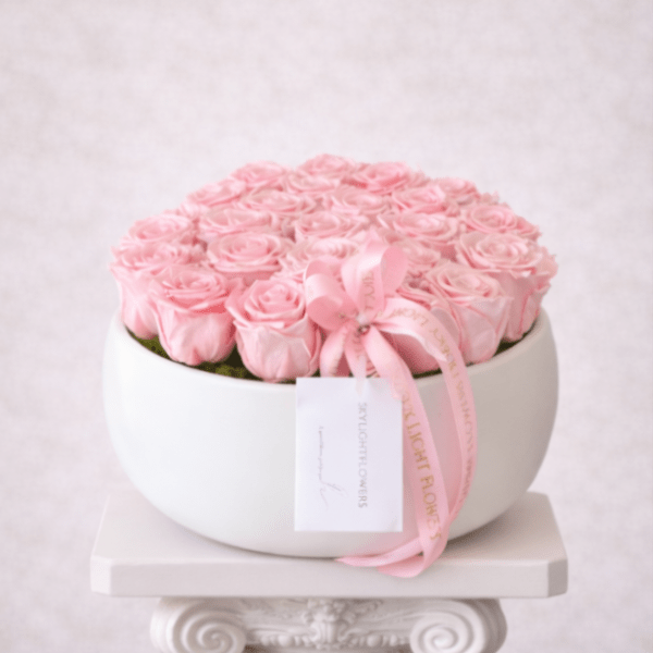 Round box of pale pink roses tied with a pink ribbon