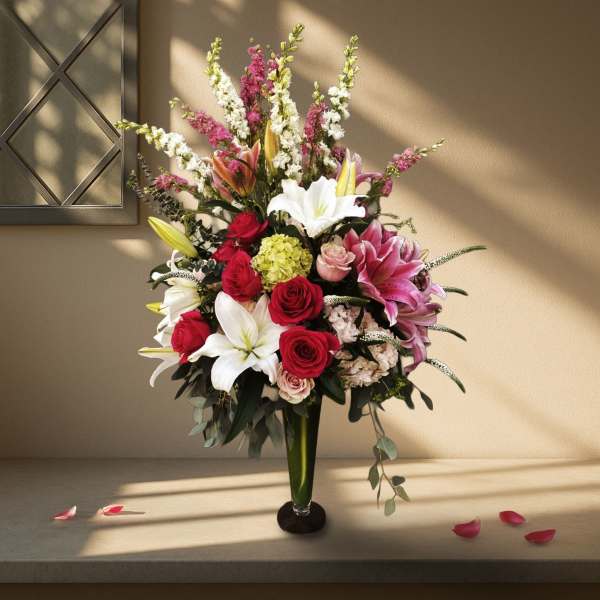Tall bouquet of red and white lilies and roses in a glass vase