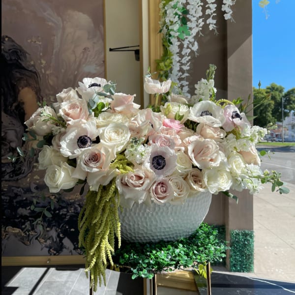 Large white and blush floral arrangement in a textured bowl vase