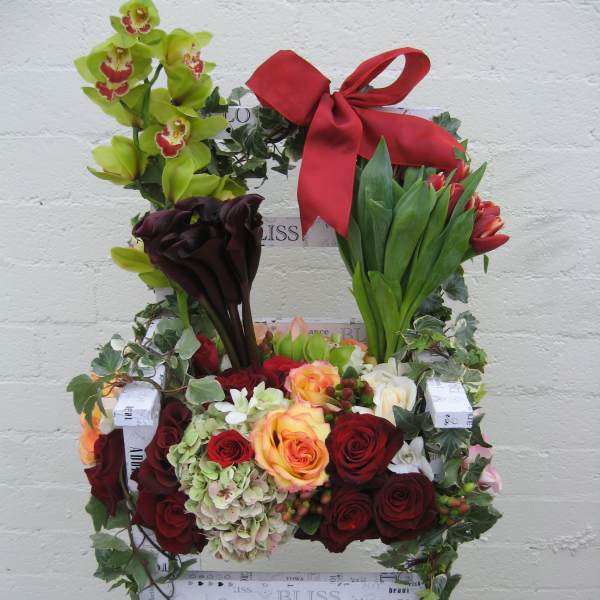 Floral chair arrangement with roses, orchids, calla lilies, and a red bow