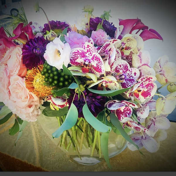 Mixed bouquet with orchids, roses, and calla lilies in a glass vase