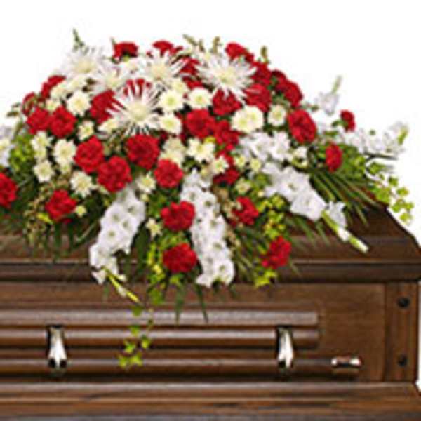 Red and white floral casket spray on a wooden casket