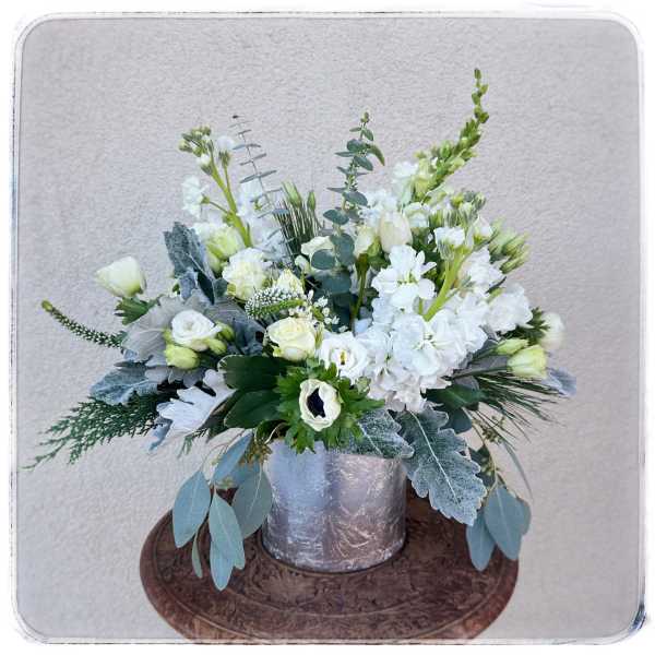 White floral arrangement in a silver container with eucalyptus