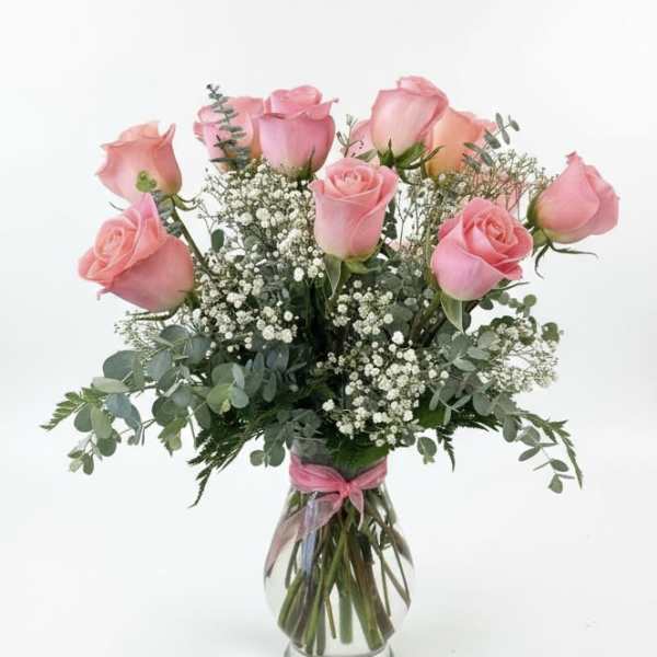 Pink roses arranged in a clear glass vase with baby's breath