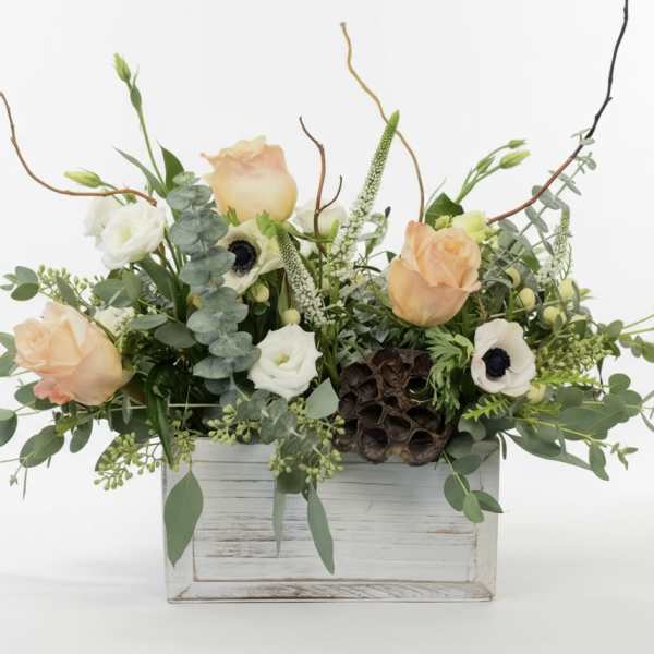 Peach and white roses in a white wooden box with greenery