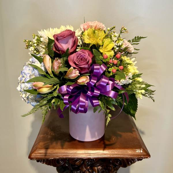 Mixed bouquet of roses, alstroemeria, and daisies in a lavender box with a purple ribbon