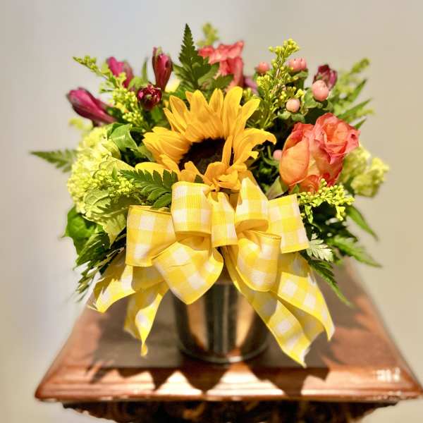 Sunflower bouquet with pink roses in a vase and yellow ribbon