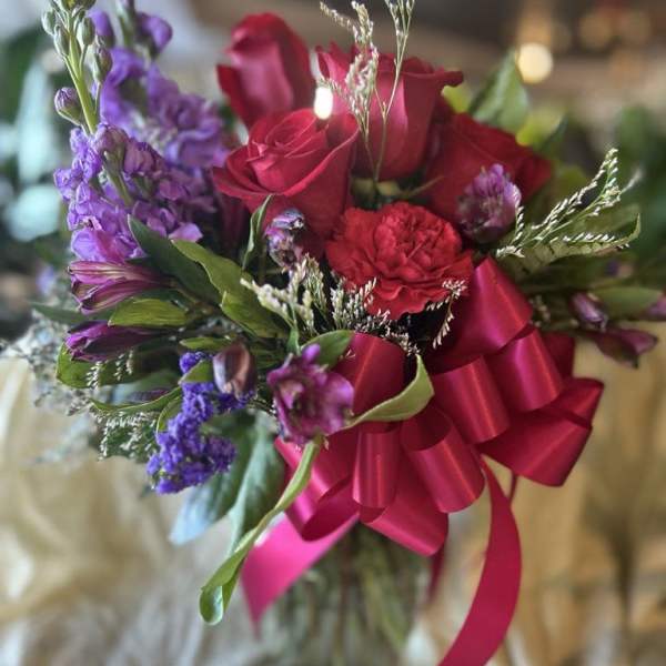 Bouquet of red roses and purple flowers with a pink ribbon