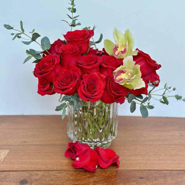 Red roses and pale orchids arranged in a clear glass vase