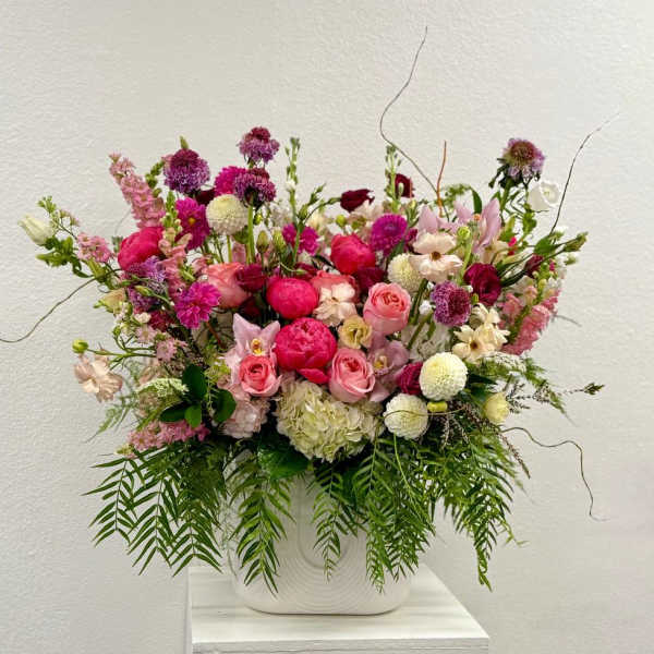 Large arrangement of pink and white mixed flowers in a white ceramic vase