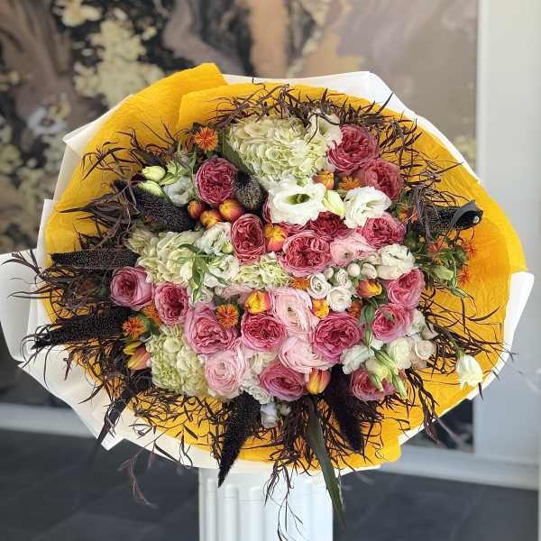 Large bouquet of pink and white flowers wrapped in yellow paper
