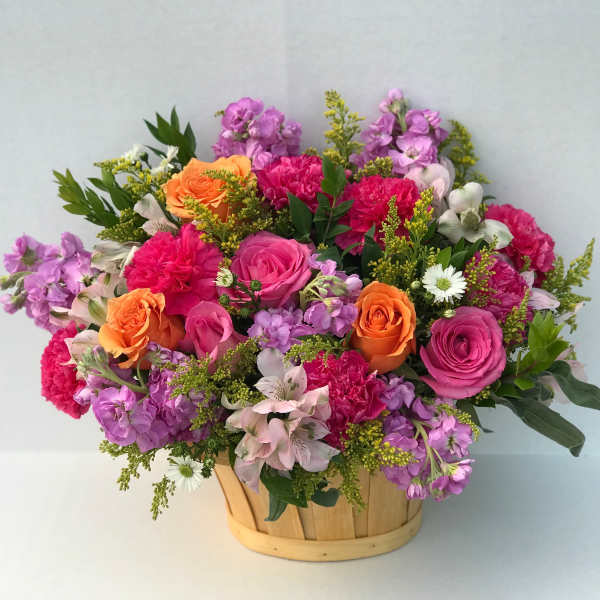 Mixed bouquet of pink, purple, and orange flowers in a wooden basket
