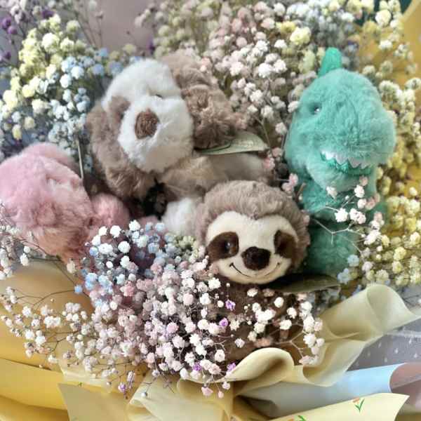 Bouquet of pastel baby’s breath surrounding small plush animals wrapped in yellow paper