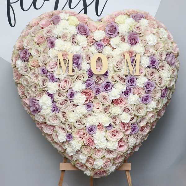 Heart-shaped floral wall with pastel roses and white blooms spelling MOM