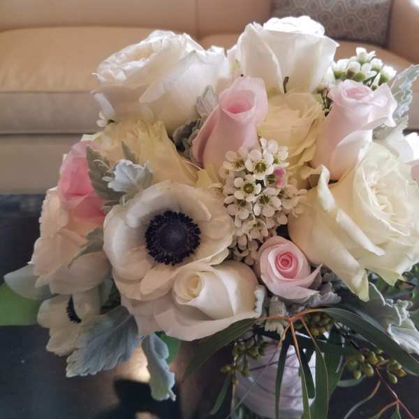 Round arrangement of white and pale pink roses with white anemones in a low vase