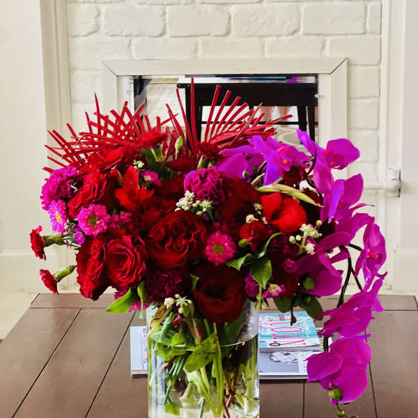 Red and magenta floral arrangement in a clear glass vase