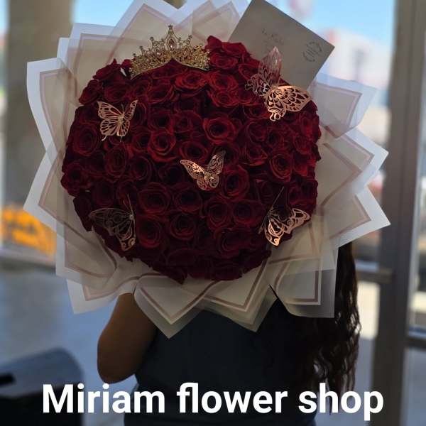 Large bouquet of deep red roses with a gold crown and butterfly decorations