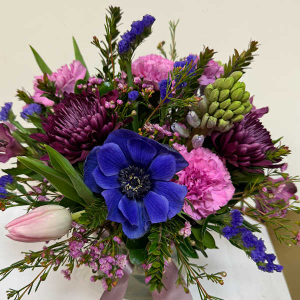 Bouquet of blue, pink, and purple flowers with a pale tulip