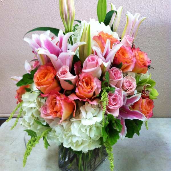 Bouquet of pink and orange roses with lilies in a glass vase
