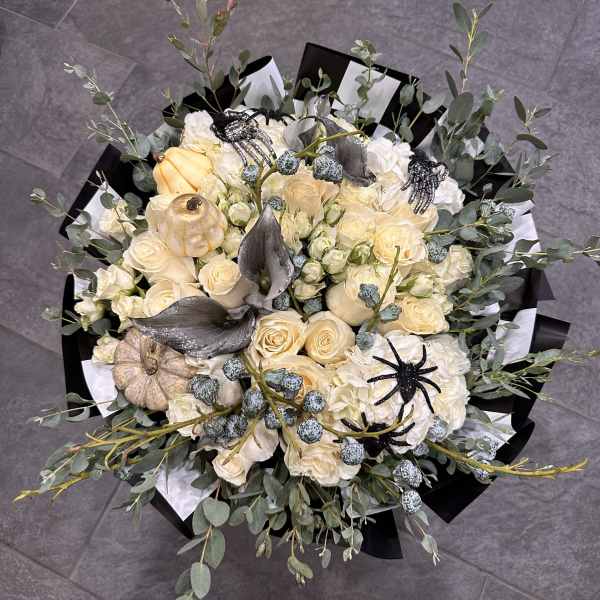 Cream rose bouquet with white hydrangeas, pumpkins, and black spider decorations