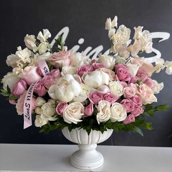 Pink and white rose arrangement in a white pedestal vase