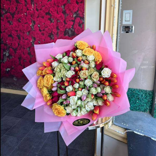 Large bouquet of roses and tulips wrapped in pink paper