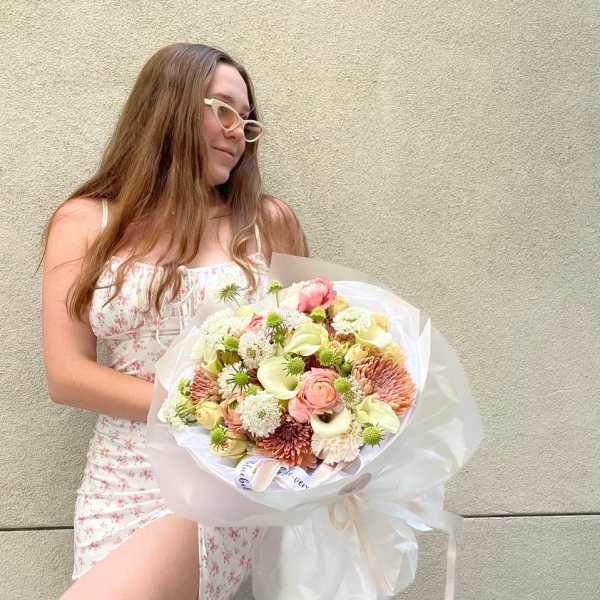 Woman holding a large pastel bouquet wrapped in white paper