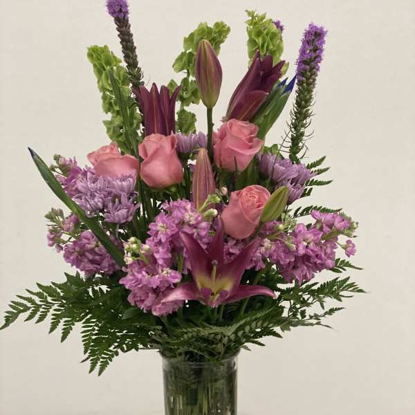 Pink roses and purple lilies in a clear glass vase
