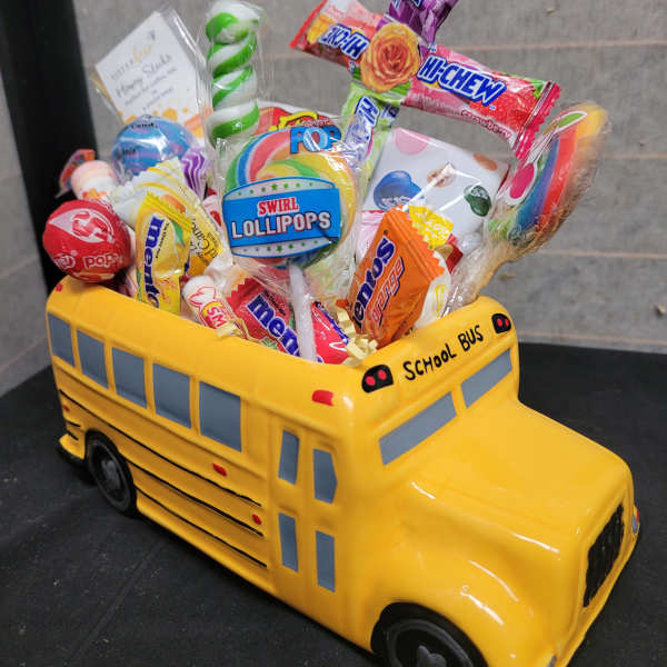 Yellow school bus-shaped candy container filled with assorted lollipops and sweets
