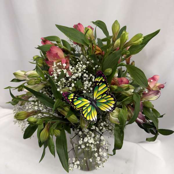 Bouquet of pink alstroemeria with baby's breath and a butterfly pick in a glass vase