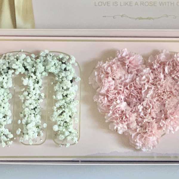 Pink heart-shaped floral box with white flower letters on each side