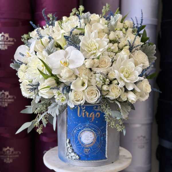 White floral arrangement in a gray hatbox with blue accents
