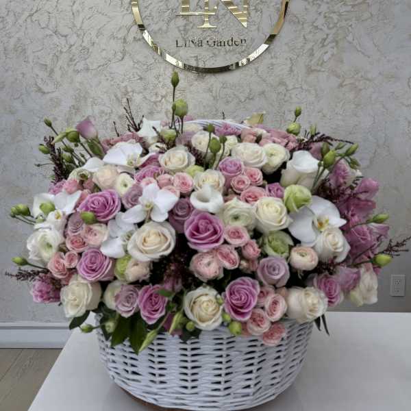 Large basket arrangement of pink and white roses with white orchids