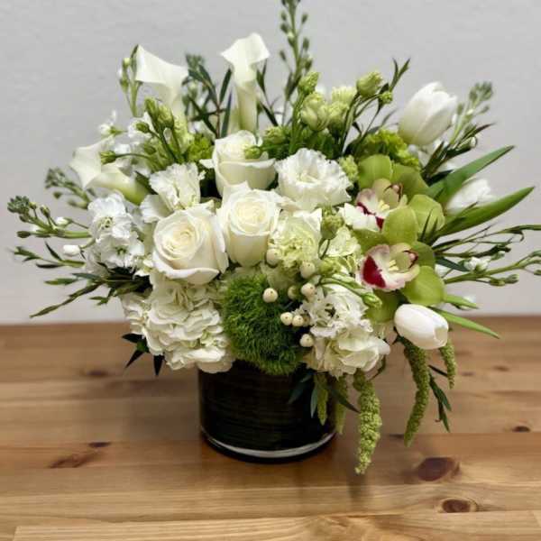 White and green floral arrangement in a black vase