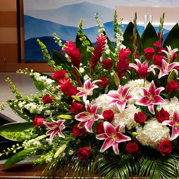 Large floral spray with pink lilies, red roses, and white hydrangeas