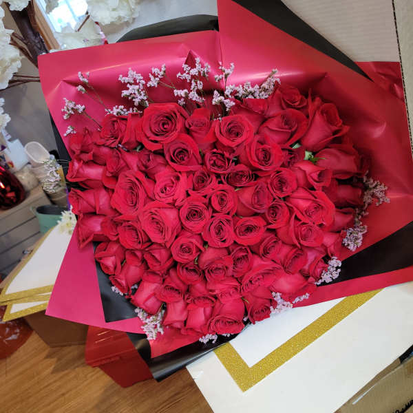 Large bouquet of red roses wrapped in pink and black paper