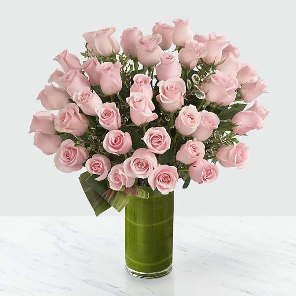 Bouquet of pale pink roses in a tall green glass vase