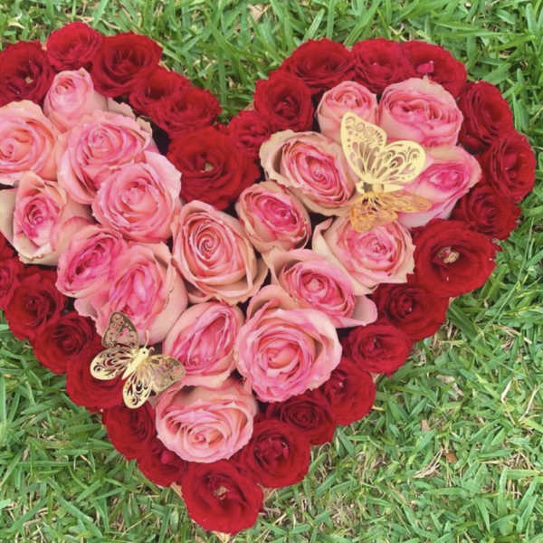 Heart-shaped rose arrangement in pink and red with butterfly accents