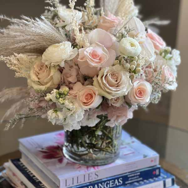 Blush and white rose bouquet in a glass vase with dried grasses