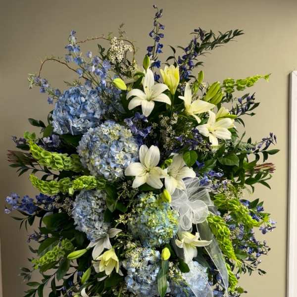 Tall standing floral spray with blue hydrangeas and white lilies