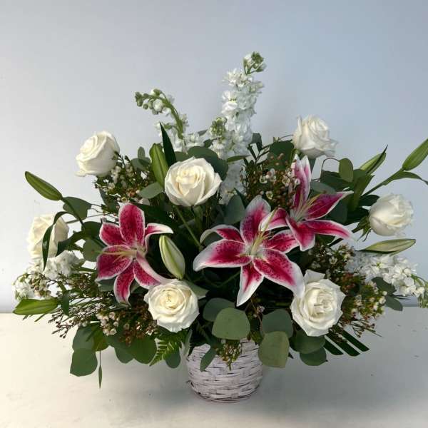 White roses and pink lilies in a white basket vase