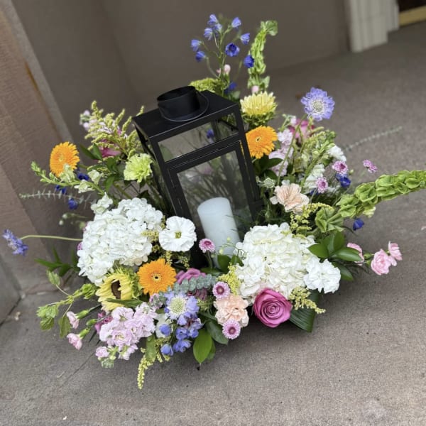 Floral wreath with a black lantern and white candle in the center