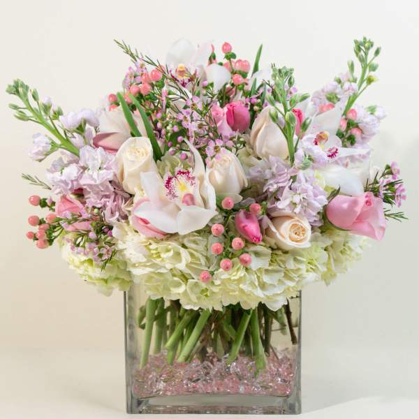Pink and white floral arrangement in a square glass vase