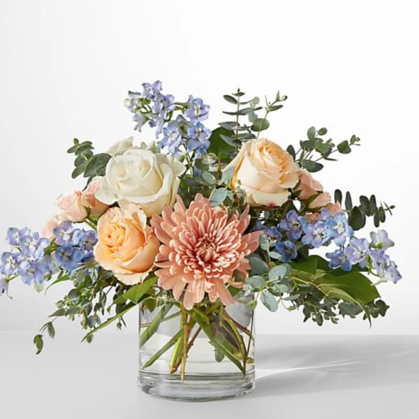 Bouquet of peach and white roses with a pink chrysanthemum in a glass vase