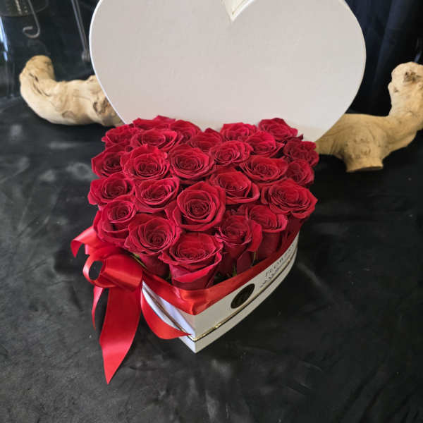 Heart-shaped box filled with red roses and a red ribbon