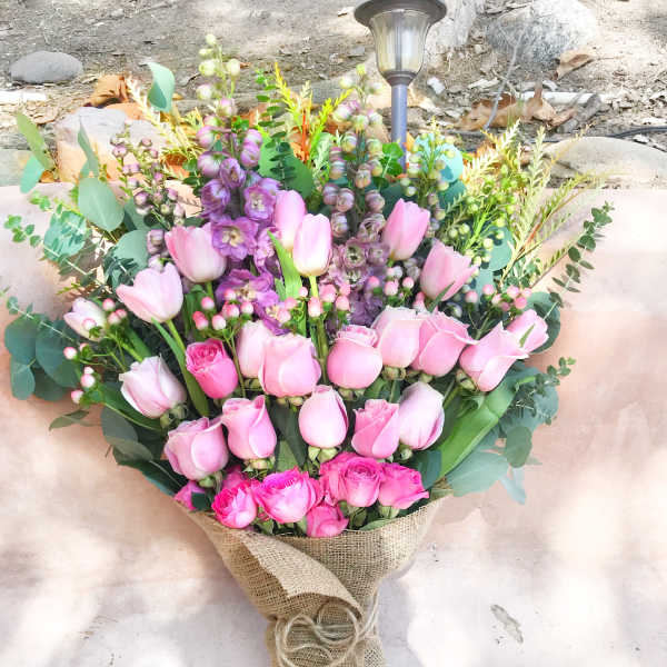 Pink tulips and roses arranged in burlap wrap